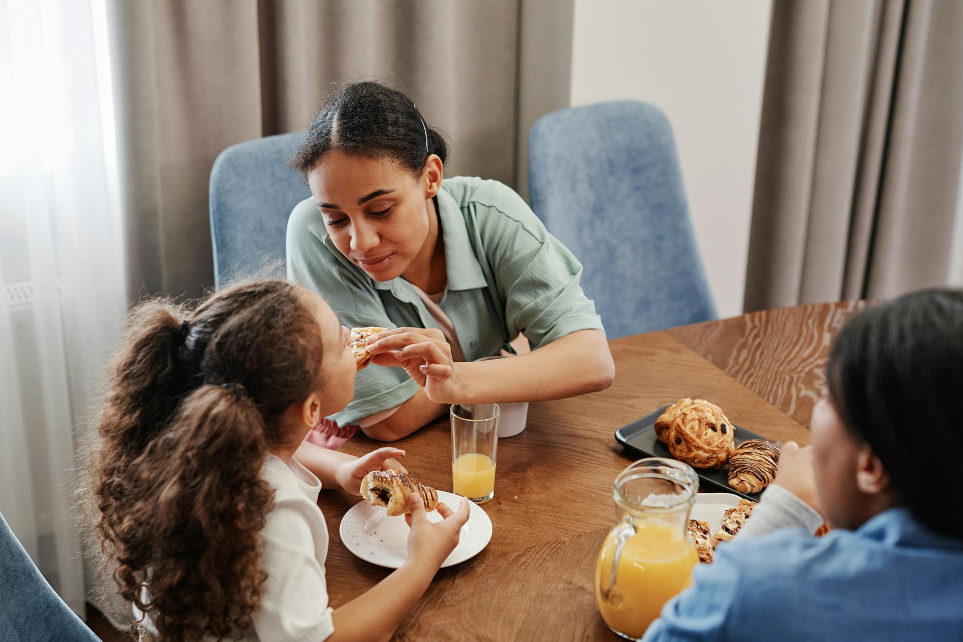 Mère et fille partageant un brunch de Fête des Mères avec viennoiseries et jus